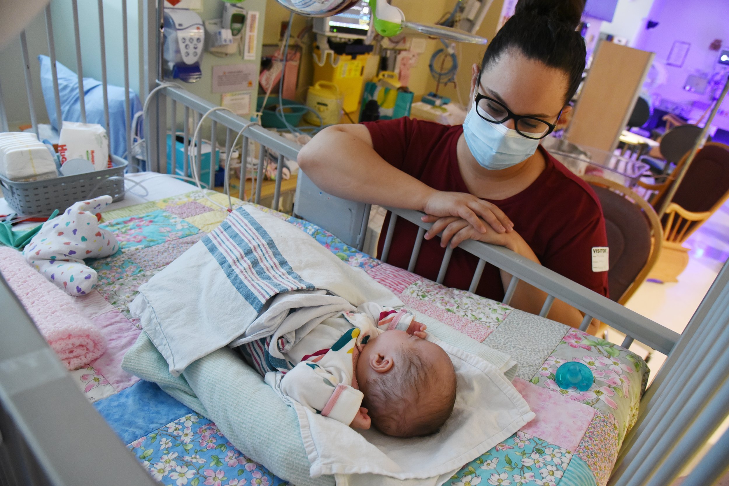 A woman looks at a baby in a hospital room